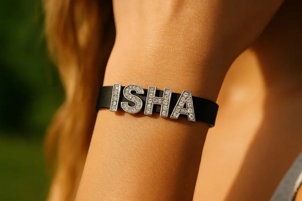 Rhinestone name bracelet in black PU leather “ISHA” letters on wrist, outdoor light