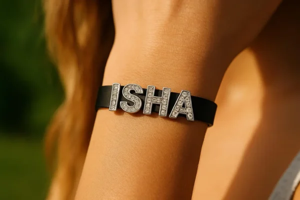 Rhinestone name bracelet in black PU leather “ISHA” letters on wrist, outdoor light