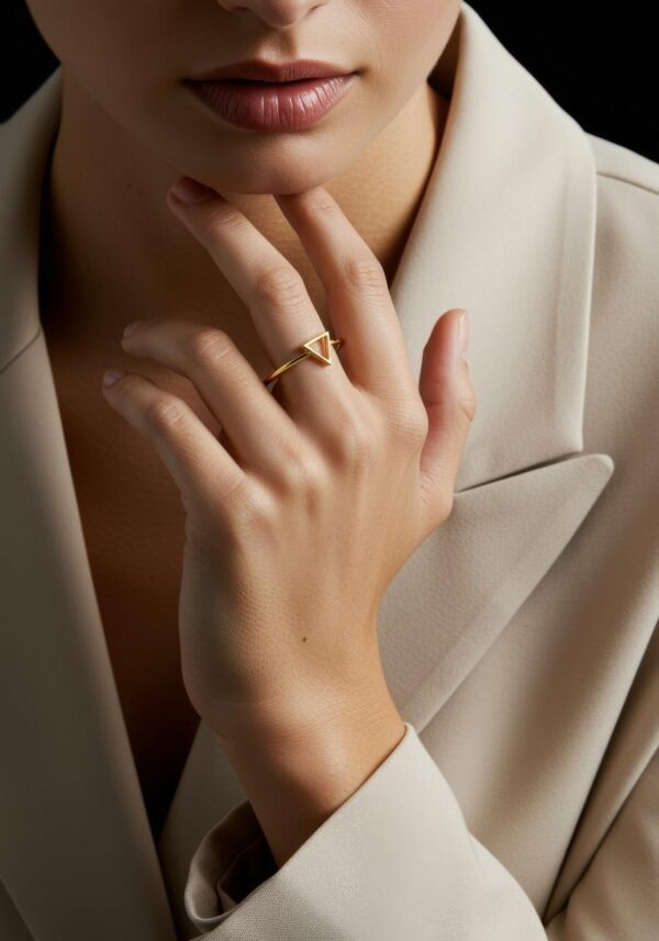 Close-up of a woman wearing a minimalist gold triangle ring on her finger